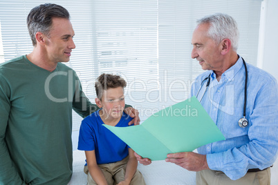 Doctor showing medical report to patient and his parent