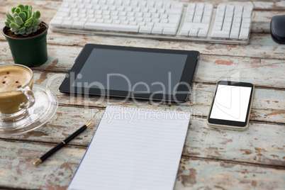 Digital tablet with computer keyboard, smartphone, pot plant, pen, notepad and coffee cup