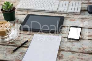 Digital tablet with computer keyboard, smartphone, pot plant, pen, notepad and coffee cup