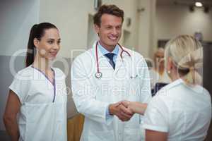 Doctor shaking hand with nurse in corridor