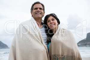 Couple wrapped in shawl on beach