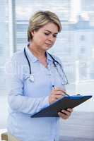 Female doctor writing on clipboard