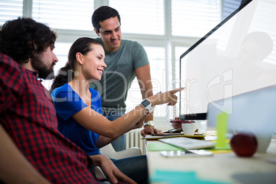 Team of graphic designers discussing over computer