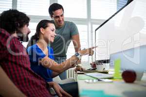 Team of graphic designers discussing over computer