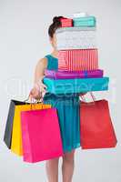 Woman carrying stack of gift boxes and shopping bags