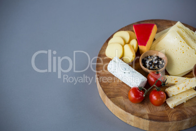 Variety of cheese with cherry tomato and spices on wooden board