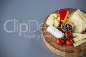 Variety of cheese with cherry tomato and spices on wooden board