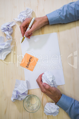 Graphic designer writing business on sticky note