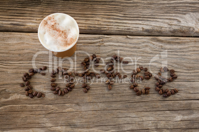 Coffee beans arranged in coffee word with disposable cups