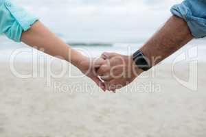 Close-up of couple holding hands on beach