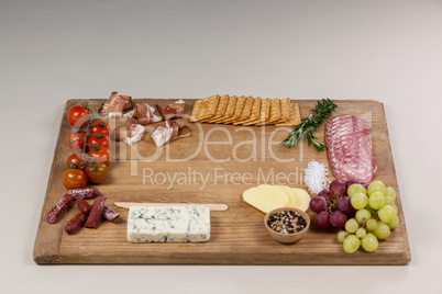 Roquefort cheese, biscuits and ham with various ingredients on chopping board