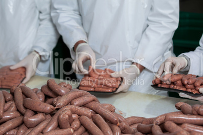 Butchers packing raw sausages
