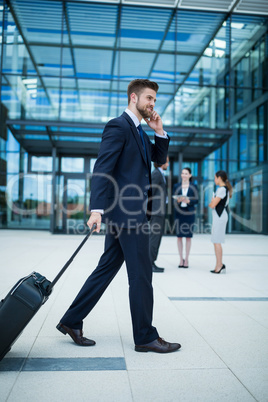 Businessman holding suitcase talking on mobile phone
