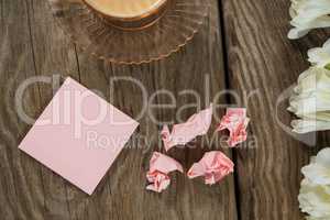 Flowers, crumbled sticky notes and coffee on wooden table