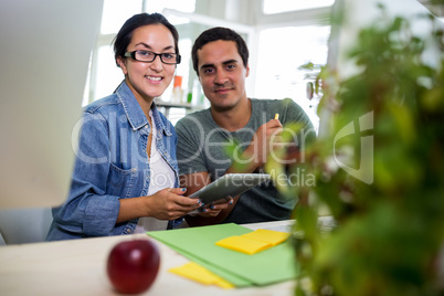 Graphic designers using digital tablet at desk