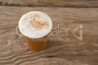 Coffee in disposable cup on wooden table