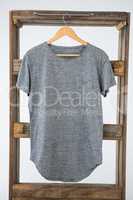 Grey t-shirt hanging on wooden frame