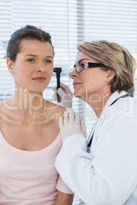 Doctor examining patients ear with otoscope