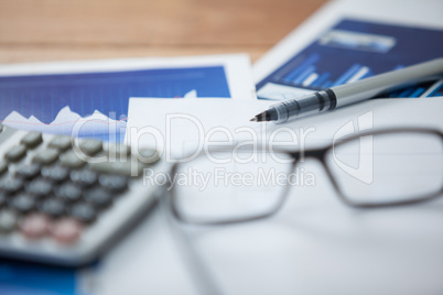 Paper document with business graph, pen, calculator and spectacles