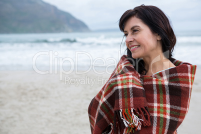 Happy woman wrapped in shawl on beach