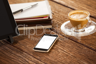 Digital tablet with smartphone and cup of coffee on wooden table