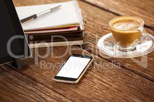 Digital tablet with smartphone and cup of coffee on wooden table