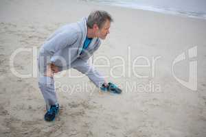Man performing stretching exercise on beach