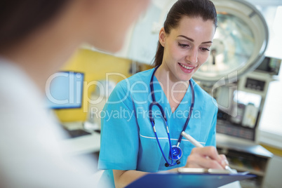 Female nurse writing on clipboard