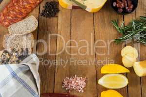 Gouda cheese, sweet lime, meat, bread slices, black pepper and rosemary on wooden board