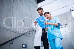 Doctor and nurse discussing over a report while climbing down stairs
