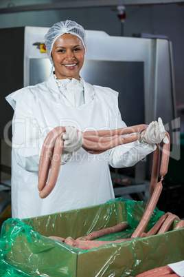 Female butcher processing sausages