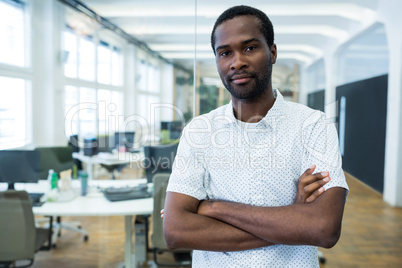 Graphic designer standing with arms crossed in office