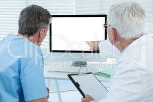 Surgeon and doctor discussing over personal computer