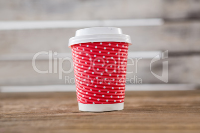 Disposable coffee cup with polka dots on wooden table
