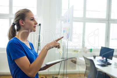 Female graphic designer looking at color chart while holding digital tablet