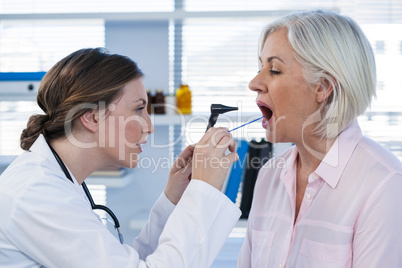 Doctor examining patients teeth with otoscope