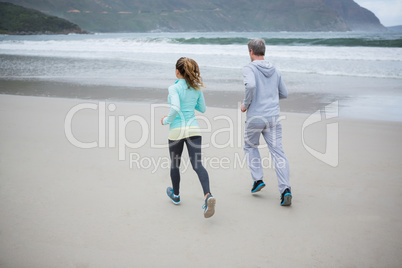 Rear view of couple jogging on beach