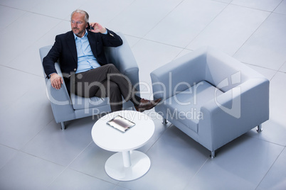 Businessman sitting on a chair and talking on mobile phone