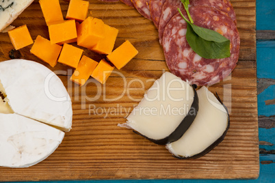 Variety of cheese with ham on chopping board