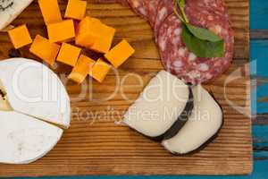 Variety of cheese with ham on chopping board