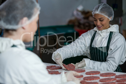 Female butchers processing hamburger patty