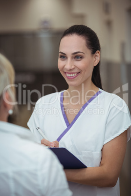 Female nurse interacting with patient in corridor