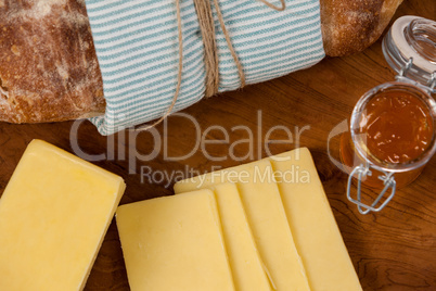 Bread loaf with slices of cheese and sauce on wooden serving board