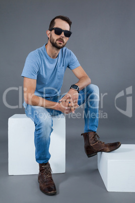 Man in blue t-shirt and sunglasses sitting on a block