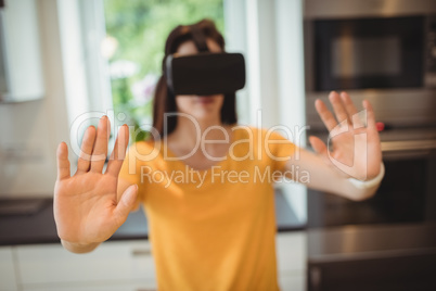Beautiful woman using virtual reality headset in kitchen