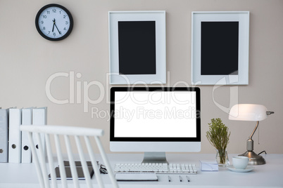 Desktop pc on desk with picture frames on wall