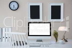 Desktop pc on desk with picture frames on wall