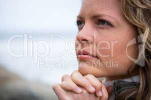 Thoughtful woman with hands clasped at the beach