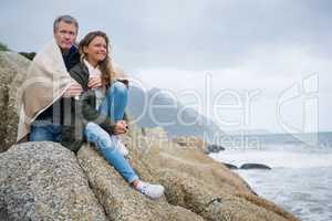 Couple wrapped in shawl sitting on rocks