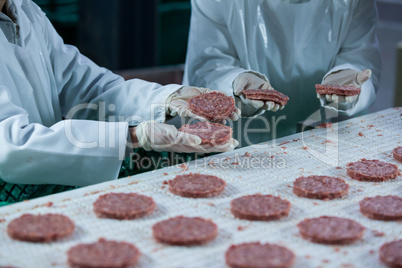 Butchers processing hamburger patty